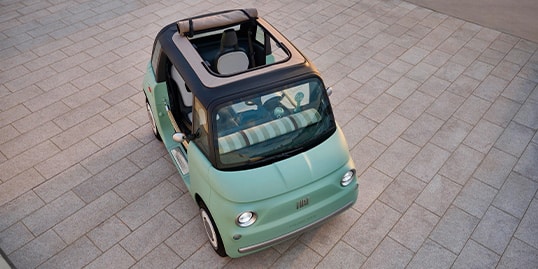 A raised angle of a mint green Fiat Topolino highlighting its open sunroof.