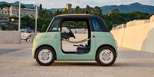 A driver-side profile of a mint green Fiat Topolino Dolcevita with door ropes.